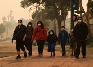 A family wearing N95 masks evacuates Paradise, which remains permeated with hazardous smoke from the Camp Fire.