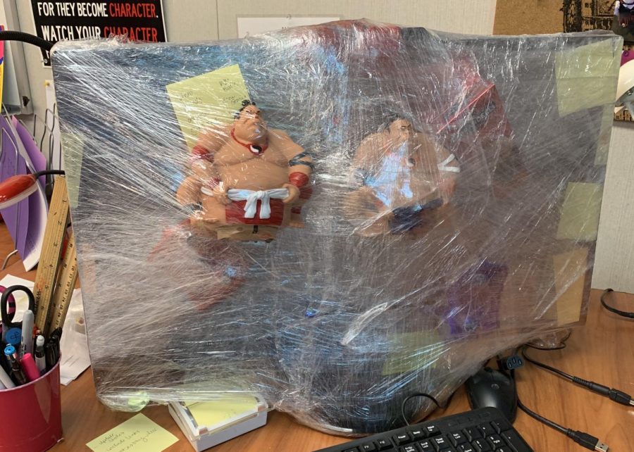Mr. Clemente attaches robotic sumo wrestlers to Mrs. Oji-Marchese’s desktop with several layers of saran wrap.