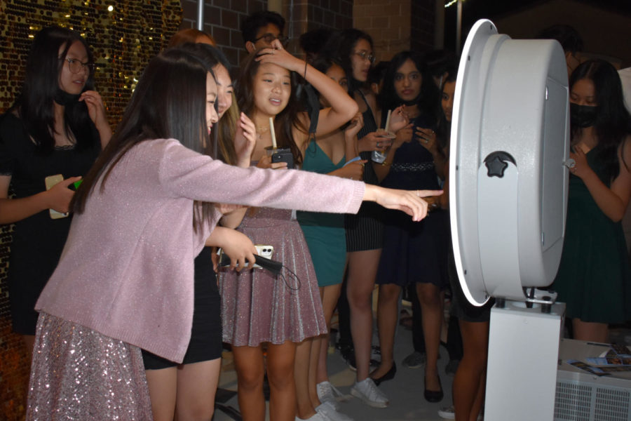A group of friends at the photo booth eagerly await their selfies.