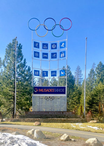 A sign has the words Palisades Tahoe with large olympic rings at the top