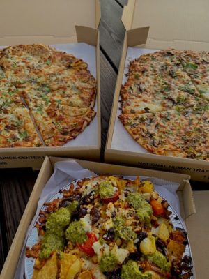 Three pizzas in their respective boxes are pictured.