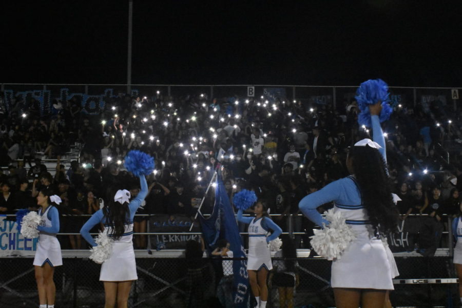 Cheerleaders+garner+enthusiasm+from+the+crowd%2C+which+is+using+their+phone+flashlight+to+light+up+the+bleachers+area+in+the+night
