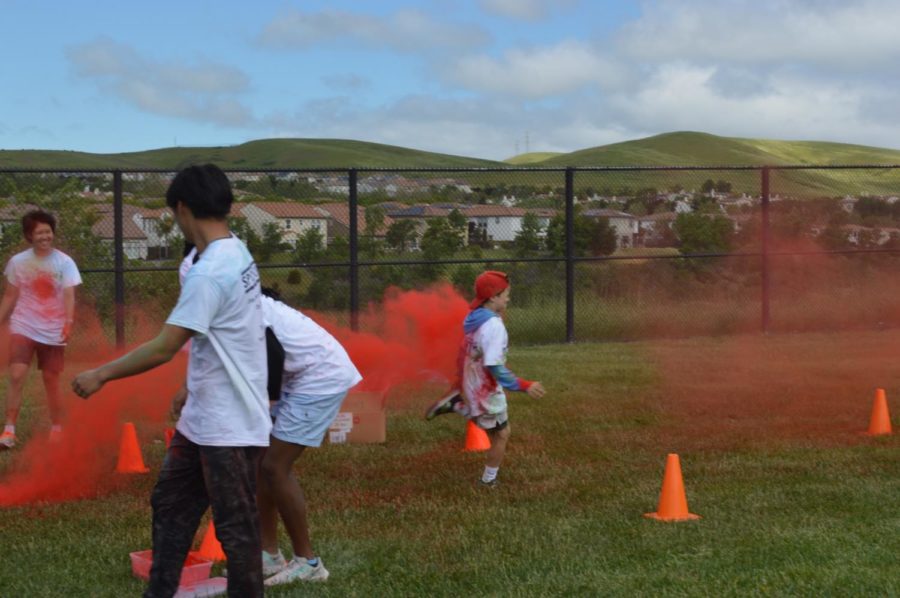  A young boy runs through red powder during the race, staying in between the orange cones. 