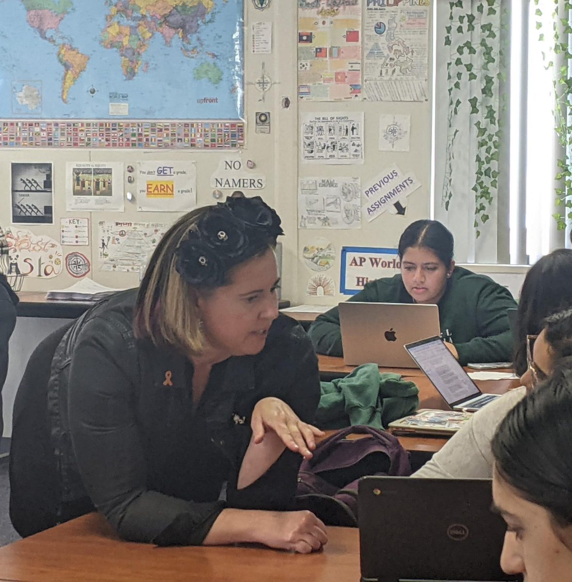 DVHS Counselor Carrie Fox leans in to read a student’s essay at a college application workshop while DVHS Senior Navya Rawal (behind) works on her application nearby.