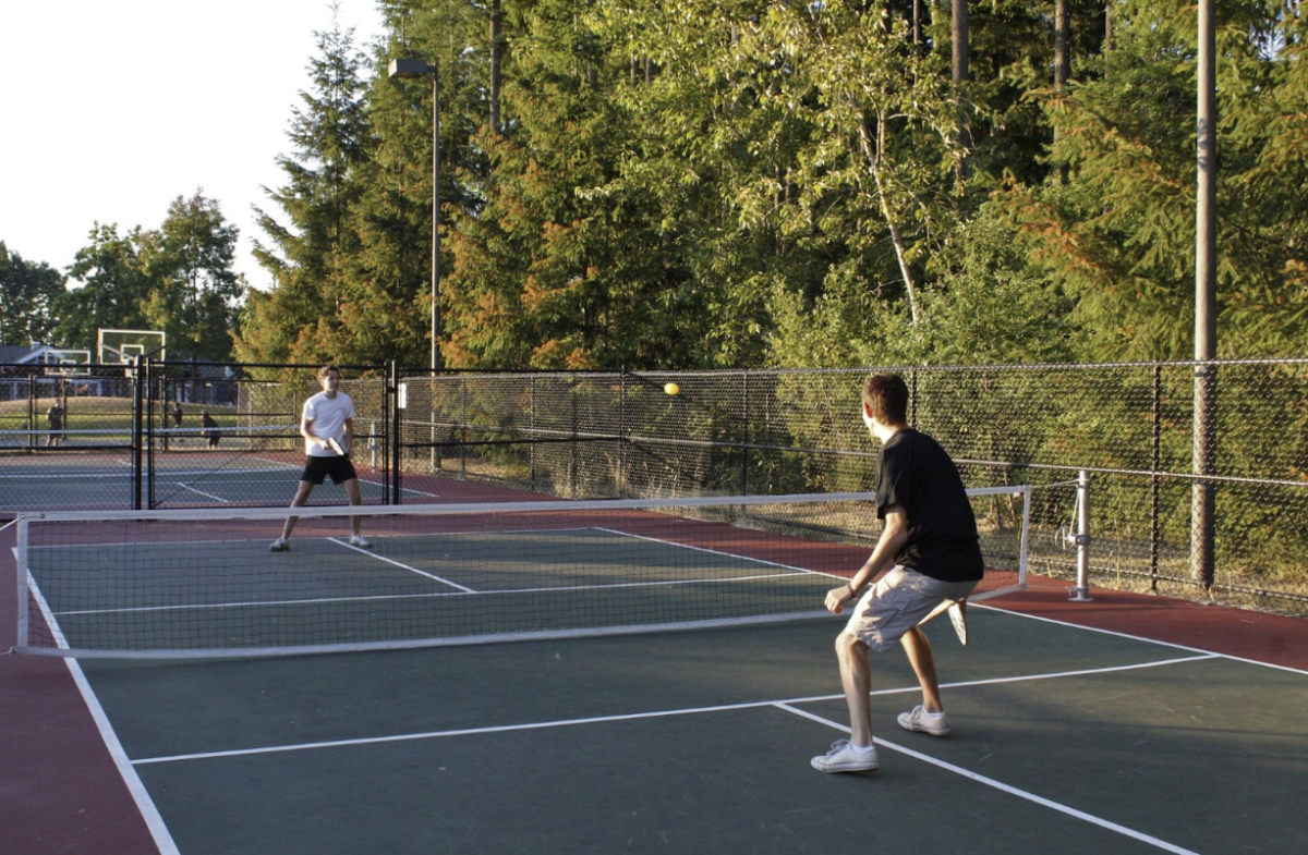 Two people playing pickleball on a court.