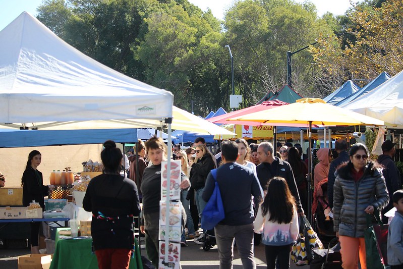 People walking around the busy farmers market.